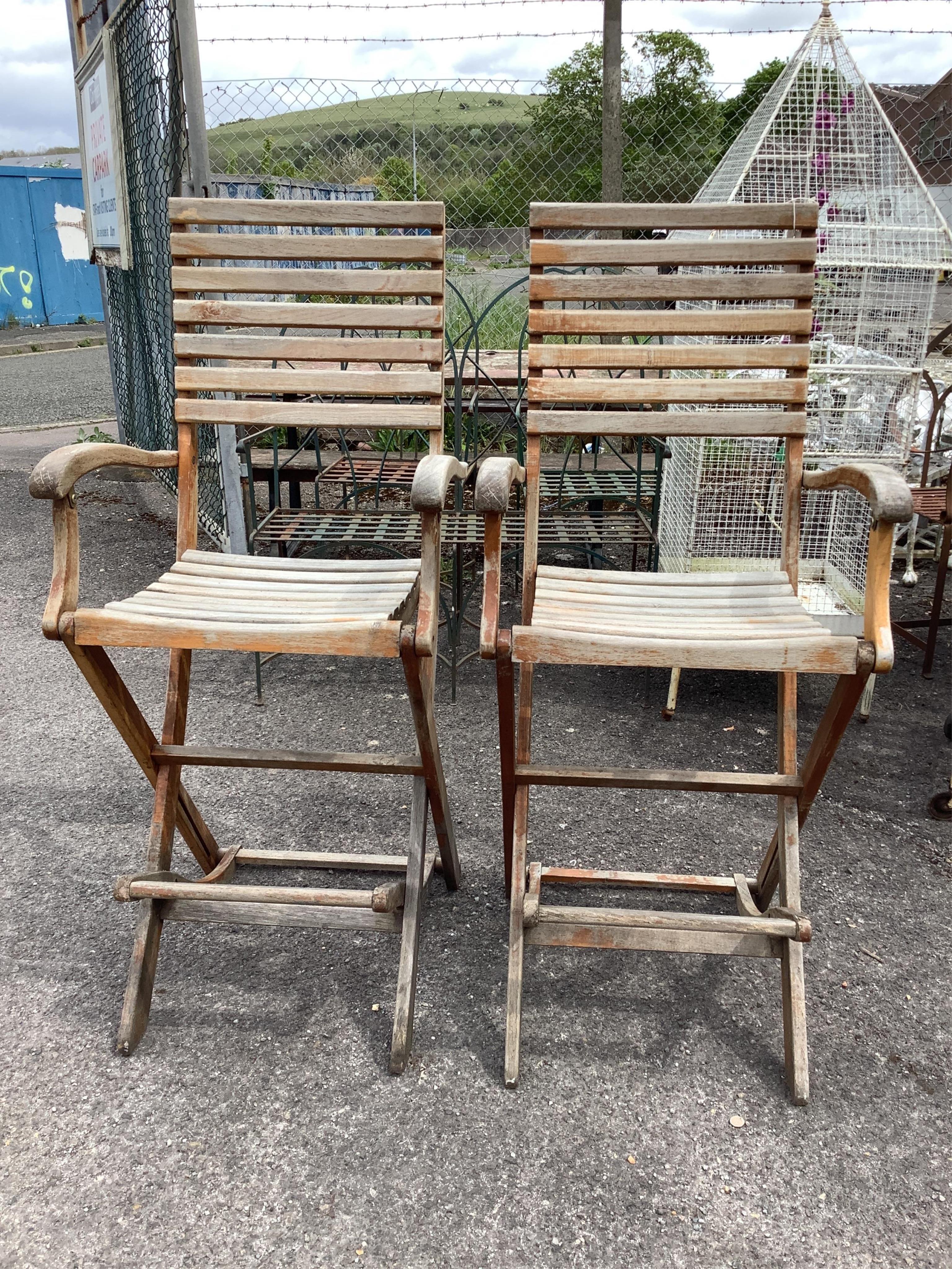 A pair of weathered teak folding garden bar chairs, width 57cm, height 130cm. Condition - fair